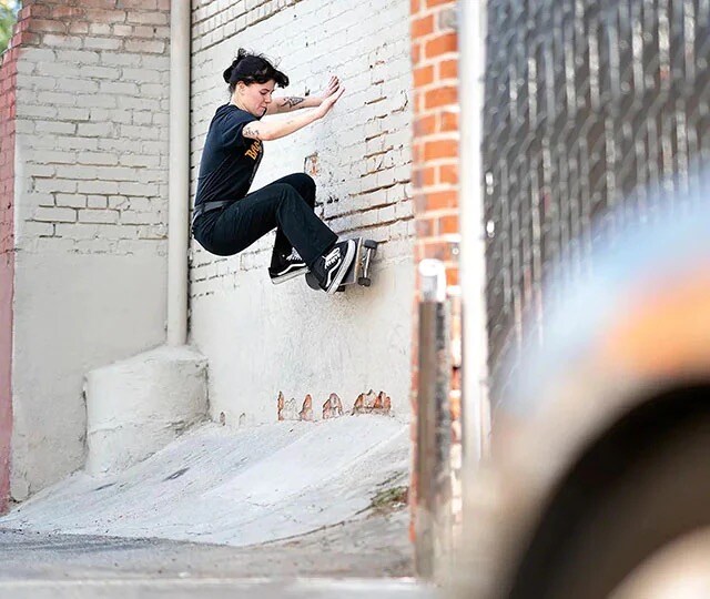 Male skateboarder jumping an orange bollard